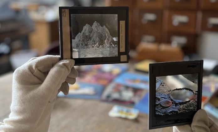 Zdjęcie przedstawia zabałaganione wnętrze i dłonie w rękawiczkach trzymające stare negatywy